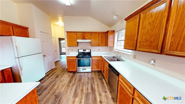 kitchen with light wood-type flooring, sink, vaulted ceiling, and stainless steel appliances