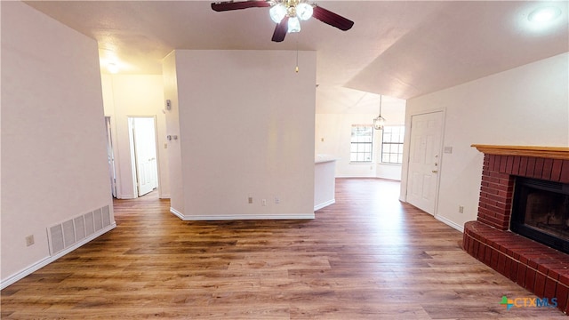 unfurnished living room featuring a fireplace, vaulted ceiling, wood-type flooring, and ceiling fan