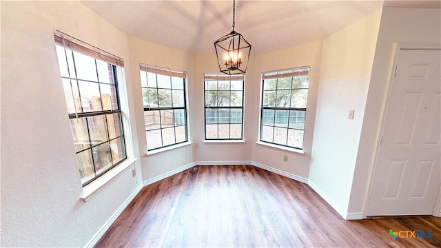 unfurnished dining area with hardwood / wood-style flooring and a notable chandelier