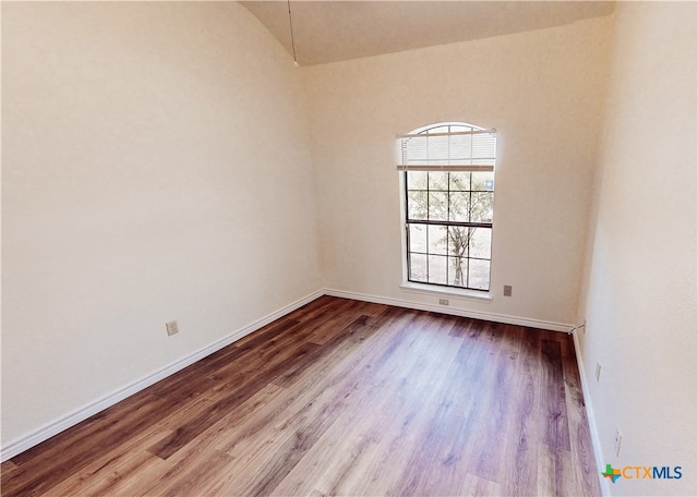 spare room featuring vaulted ceiling and hardwood / wood-style flooring