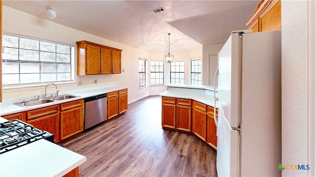 kitchen featuring a wealth of natural light, sink, stainless steel dishwasher, white fridge, and decorative light fixtures