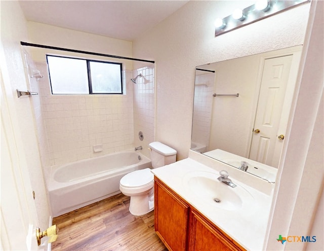 full bathroom with wood-type flooring, tiled shower / bath combo, toilet, and vanity