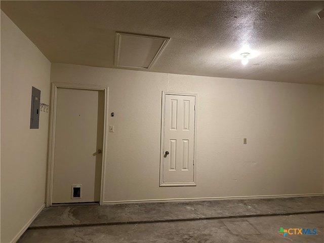 empty room with electric panel and a textured ceiling