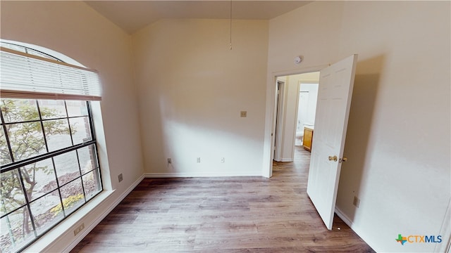 spare room featuring vaulted ceiling and hardwood / wood-style flooring