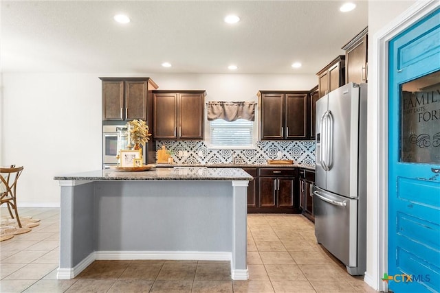 2014 Deer Field Way, Harker Heights, TX 76548 - kitchen featuring appliances with stainless steel finishes, dark stone counters, dark brown cabinets, a kitchen island, and decorative backsplash