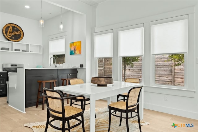 dining space with light hardwood / wood-style flooring and wet bar