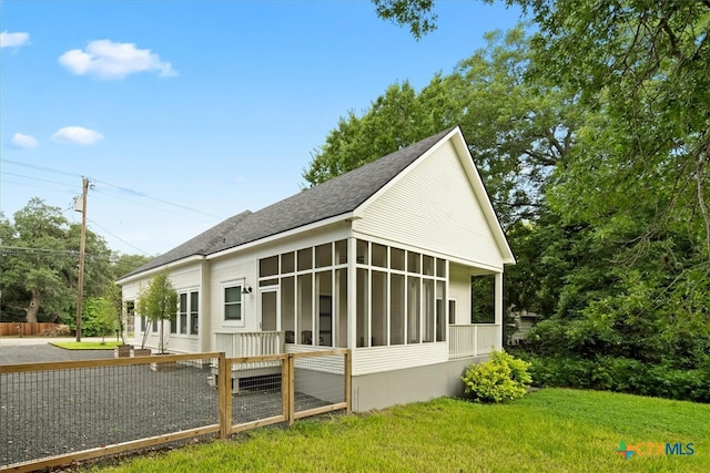 view of side of property with a sunroom and a yard