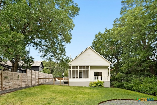 back of property featuring a lawn and a sunroom