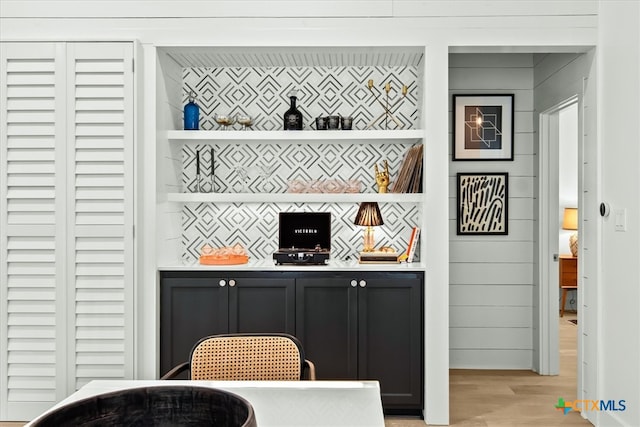 bar featuring light wood-type flooring and backsplash