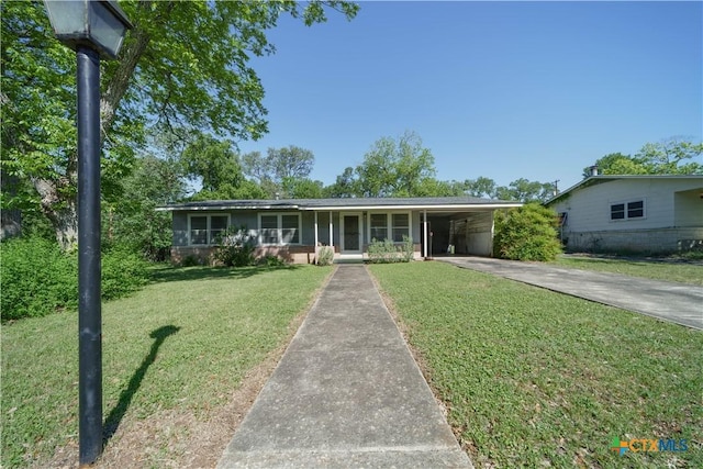ranch-style home featuring concrete driveway, a carport, and a front yard