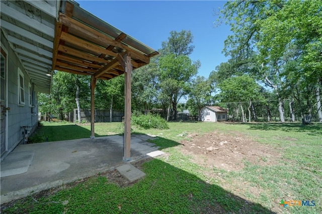 view of yard with fence, a patio area, and an outbuilding