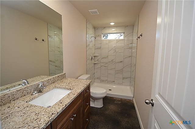 bathroom featuring a tile shower, vanity, and toilet