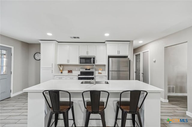 kitchen featuring white cabinetry, stainless steel appliances, and a kitchen island with sink