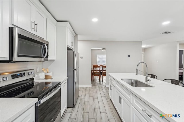 kitchen with white cabinetry, sink, ceiling fan, light stone countertops, and appliances with stainless steel finishes