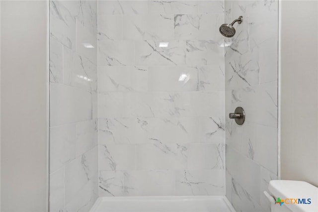 bathroom featuring a tile shower and toilet