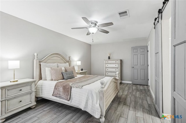 bedroom featuring ceiling fan and a barn door