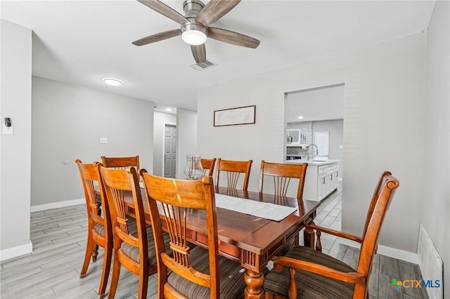 dining room with light wood-type flooring, ceiling fan, and sink