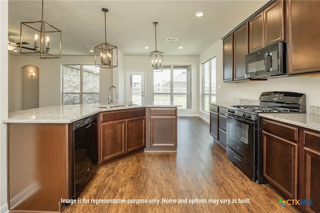 kitchen with black appliances, dark hardwood / wood-style floors, light stone countertops, hanging light fixtures, and sink