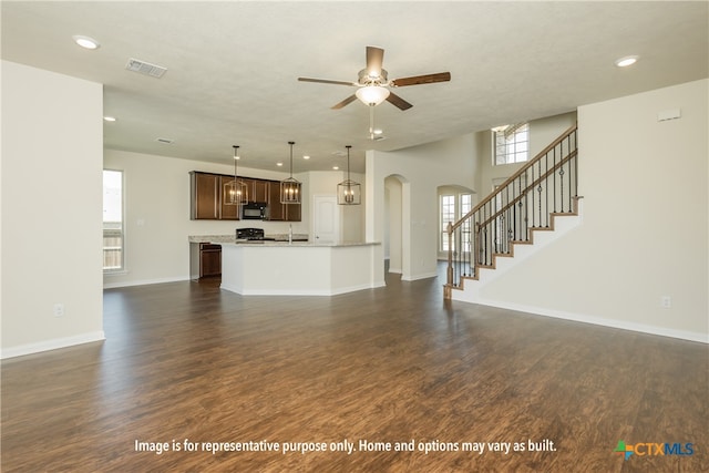 unfurnished living room featuring plenty of natural light, ceiling fan, and dark hardwood / wood-style flooring