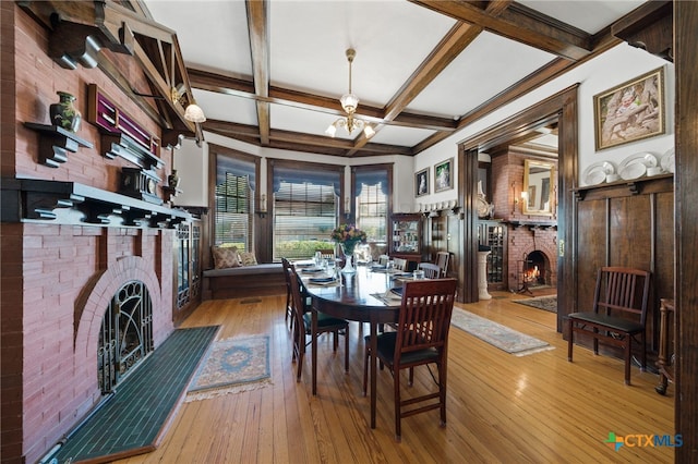 dining room with a fireplace, beam ceiling, light wood-type flooring, and coffered ceiling