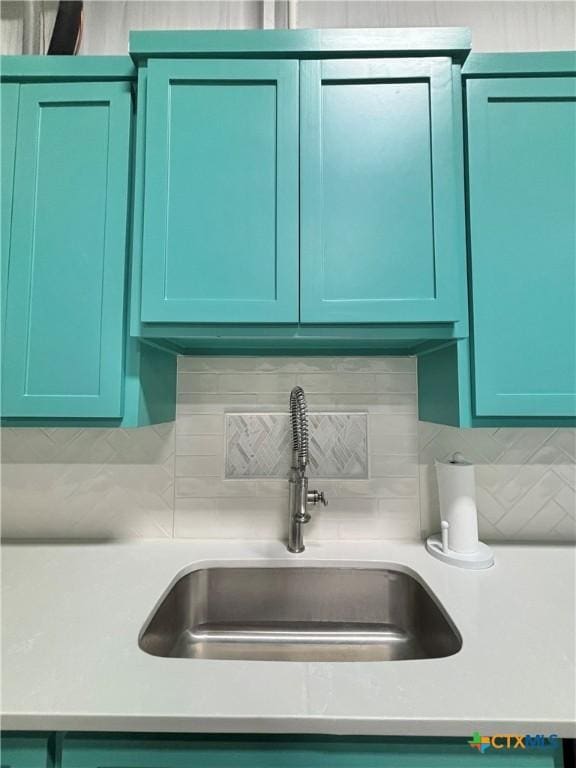 room details featuring green cabinets, decorative backsplash, and sink