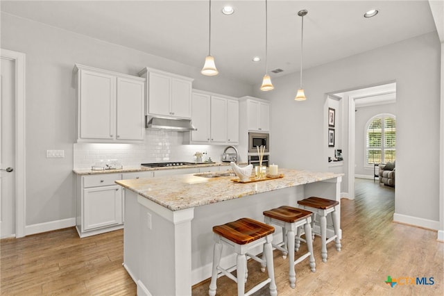 kitchen featuring white cabinets, a center island with sink, and sink