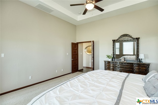 carpeted bedroom with ceiling fan and a raised ceiling