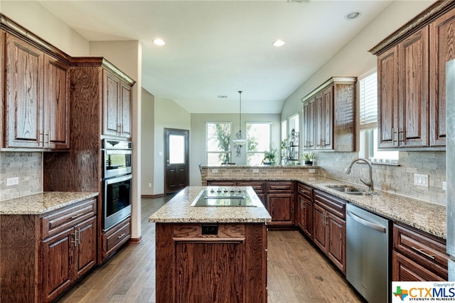 kitchen featuring tasteful backsplash, appliances with stainless steel finishes, decorative light fixtures, hardwood / wood-style flooring, and a center island