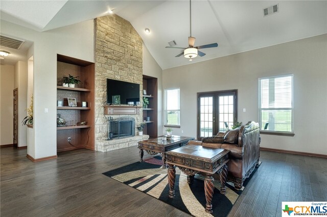 living room with built in shelves, french doors, a stone fireplace, dark hardwood / wood-style flooring, and ceiling fan