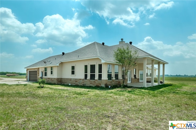 rear view of house with covered porch, a garage, and a yard