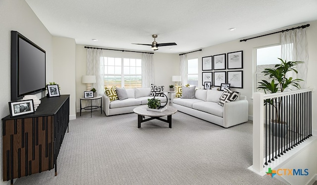 living room featuring ceiling fan, light carpet, and a textured ceiling