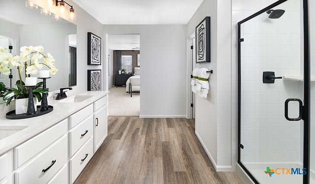 bathroom featuring hardwood / wood-style flooring, a healthy amount of sunlight, a shower with door, and vanity