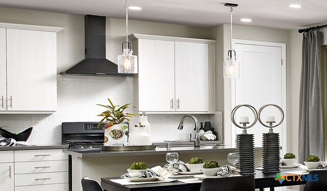 kitchen featuring pendant lighting, black range with electric cooktop, white cabinets, and wall chimney exhaust hood