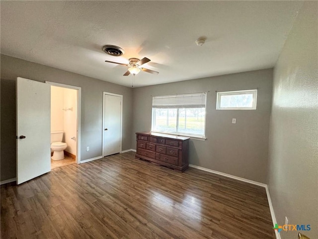 unfurnished bedroom featuring ensuite bathroom, dark hardwood / wood-style floors, and ceiling fan