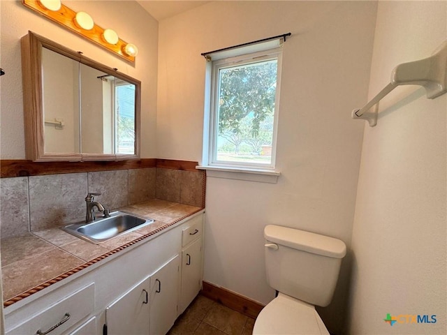 bathroom featuring toilet, backsplash, and vanity