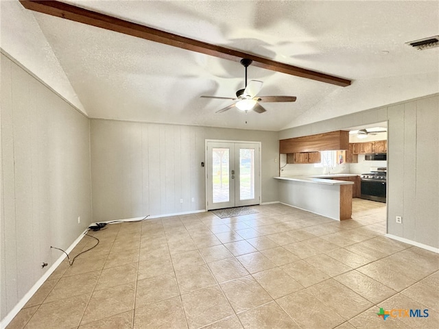 unfurnished living room with french doors, ceiling fan, lofted ceiling with beams, and a textured ceiling