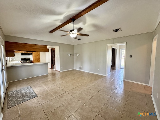 unfurnished living room with vaulted ceiling with beams, a textured ceiling, ceiling fan, light tile patterned flooring, and sink