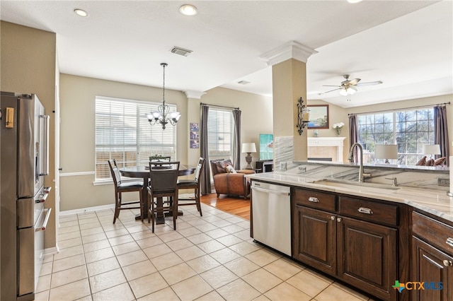 kitchen featuring sink, decorative light fixtures, dark brown cabinets, stainless steel appliances, and ceiling fan with notable chandelier