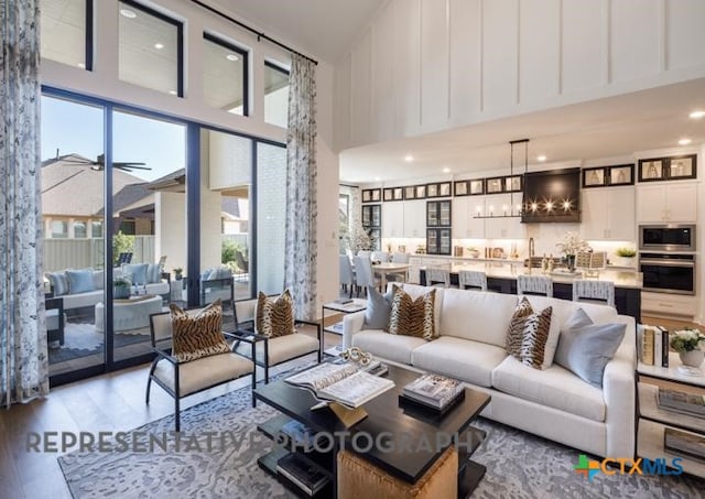 living room featuring light hardwood / wood-style flooring, a wealth of natural light, ceiling fan, and a high ceiling