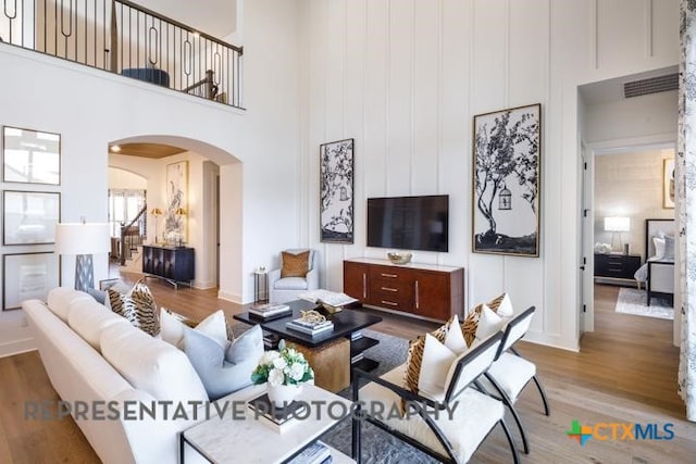 living room with hardwood / wood-style floors and a towering ceiling