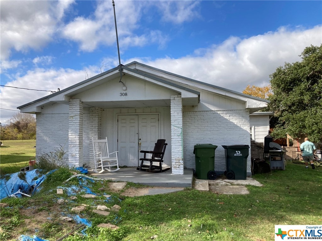 rear view of property with a lawn and covered porch