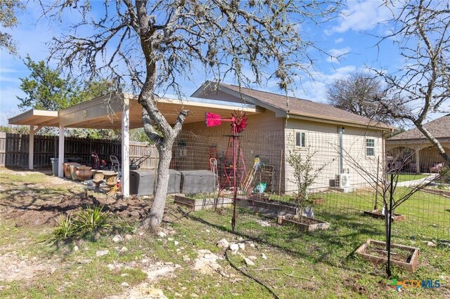 back of house with brick siding, a lawn, fence, and a garden