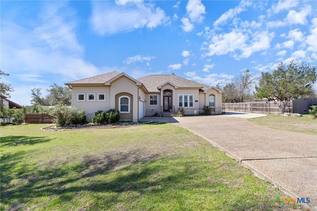 view of front of home featuring concrete driveway, a front lawn, fence, and stucco siding