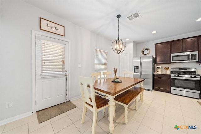 dining room with light tile patterned floors, visible vents, a healthy amount of sunlight, and a chandelier