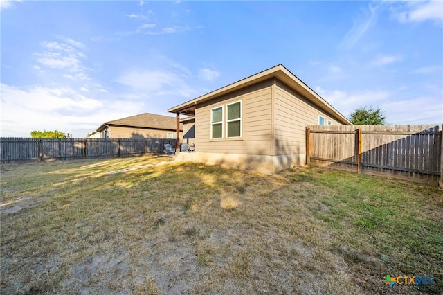 rear view of house featuring a lawn and a fenced backyard