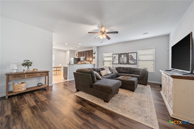 living room featuring visible vents, a ceiling fan, a textured ceiling, dark wood finished floors, and baseboards