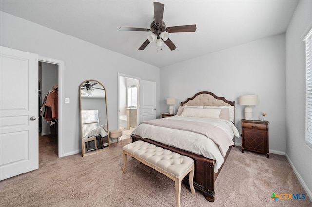 bedroom with baseboards, light carpet, ensuite bathroom, and a spacious closet