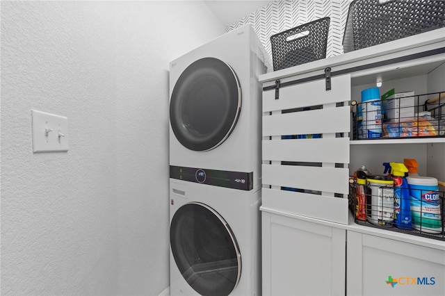 washroom with laundry area, stacked washer and clothes dryer, and a textured wall