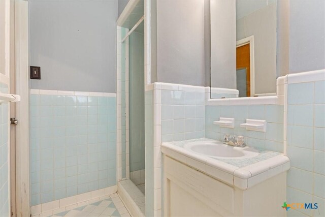302 W Upshaw Ave, Temple, TX 76501 - full bath featuring tile walls, a shower stall, vanity, wainscoting, and tile patterned flooring
