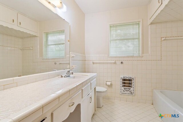 302 W Upshaw Ave, Temple, TX 76501 - full bathroom featuring heating unit, tile patterned flooring, tile walls, toilet, and vanity